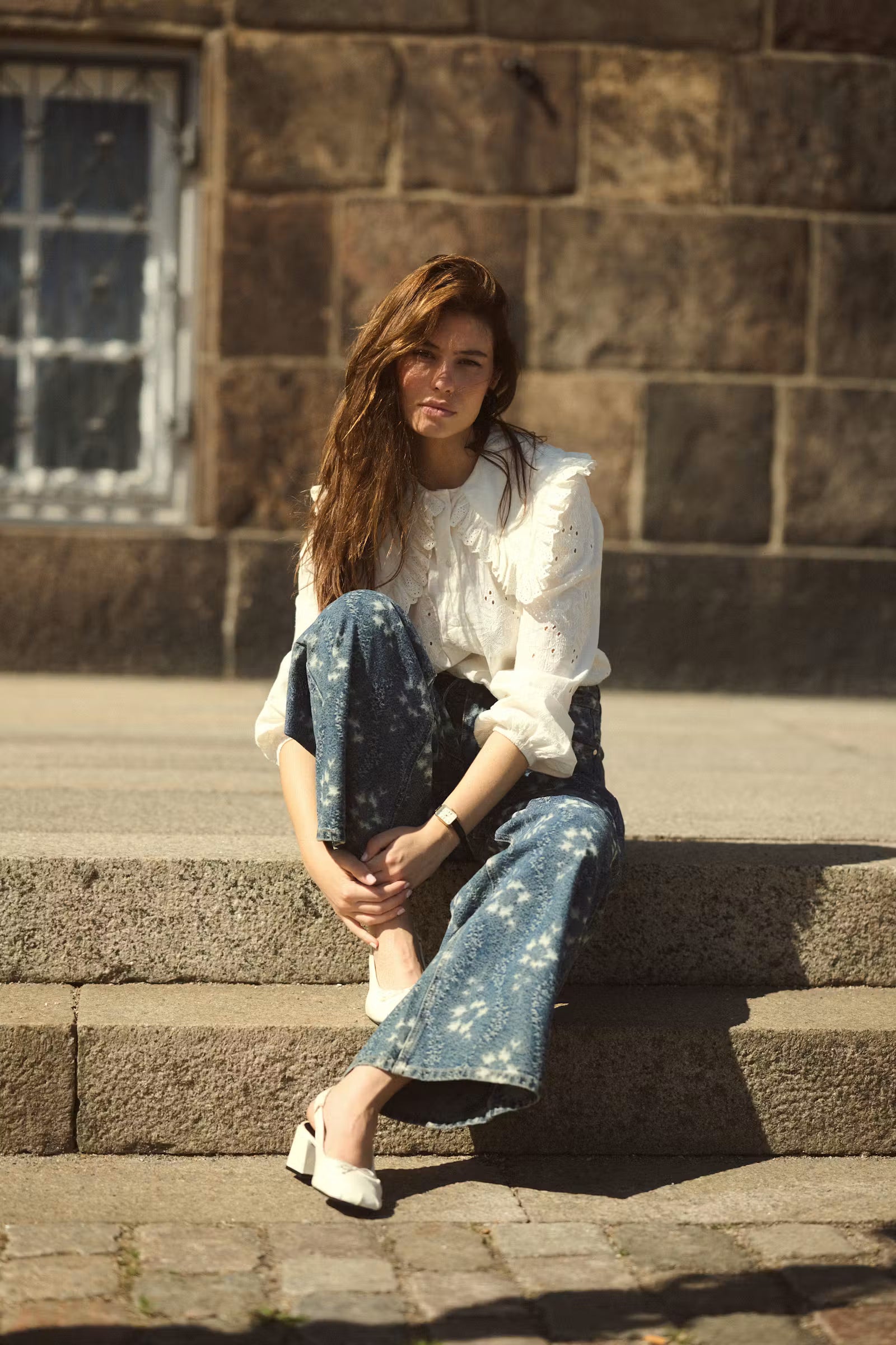 Culture Claramille white broderie anglaise blouse styled seated outdoors