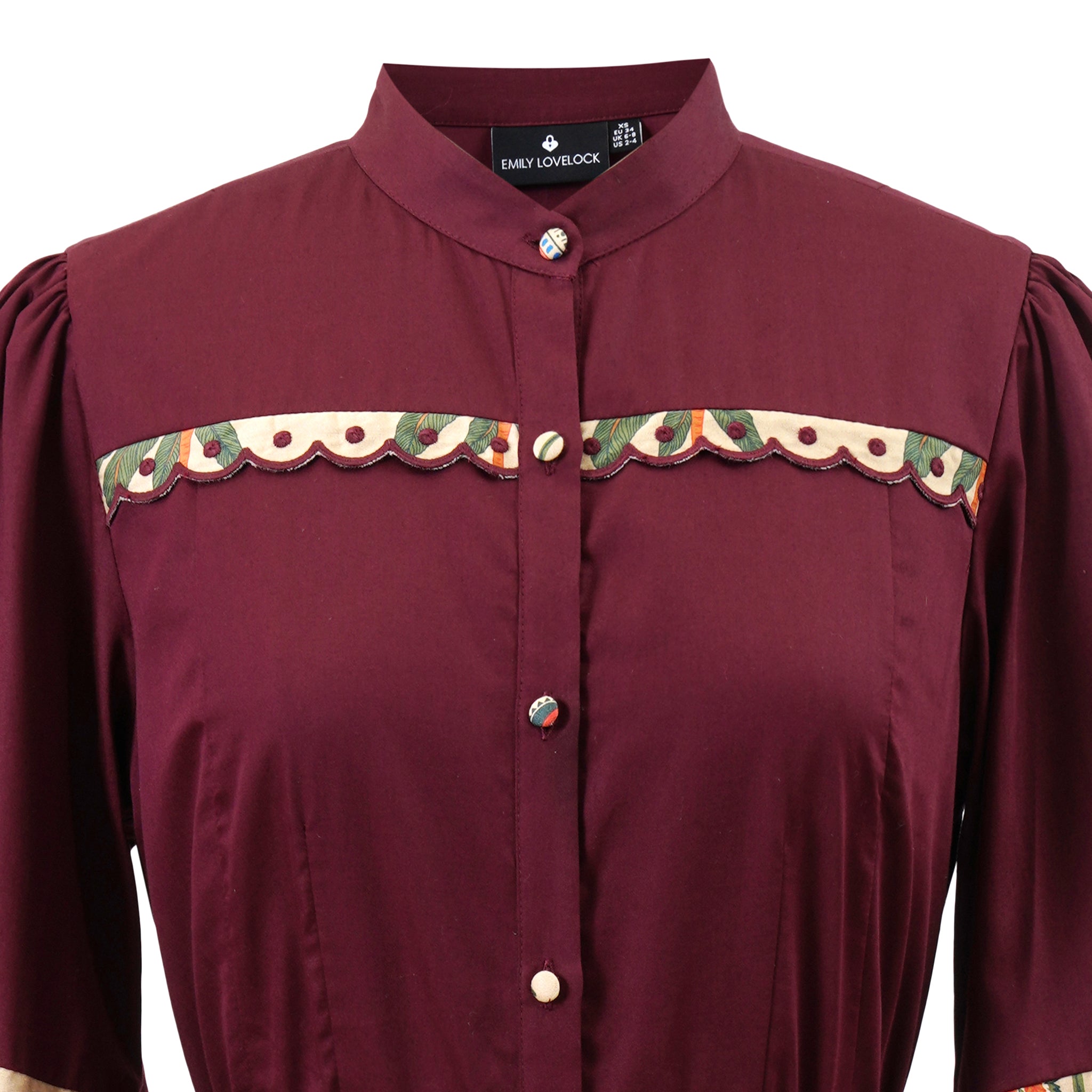 Close-up of Emily Lovelock Annette burgundy midi dress contrast trim and collar