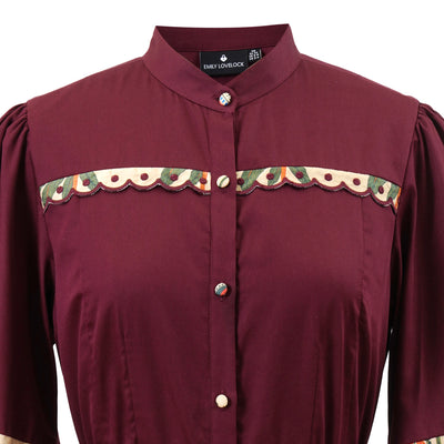Close-up of Emily Lovelock Annette burgundy midi dress contrast trim and collar