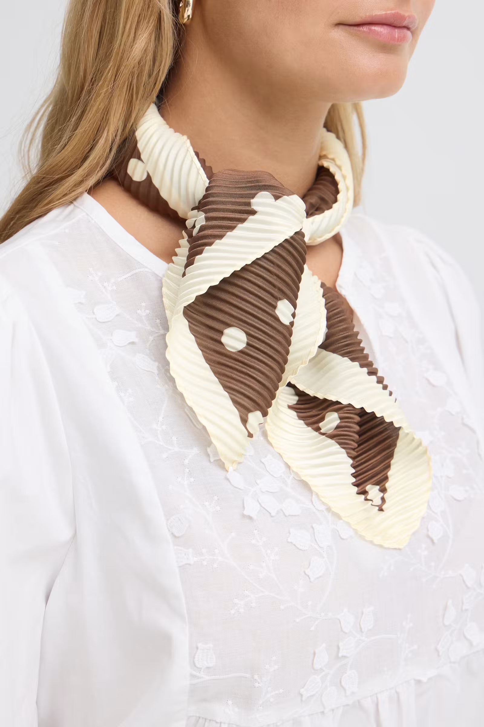Fransa Selana brown and cream polka dot neck scarf tied over a white blouse close-up