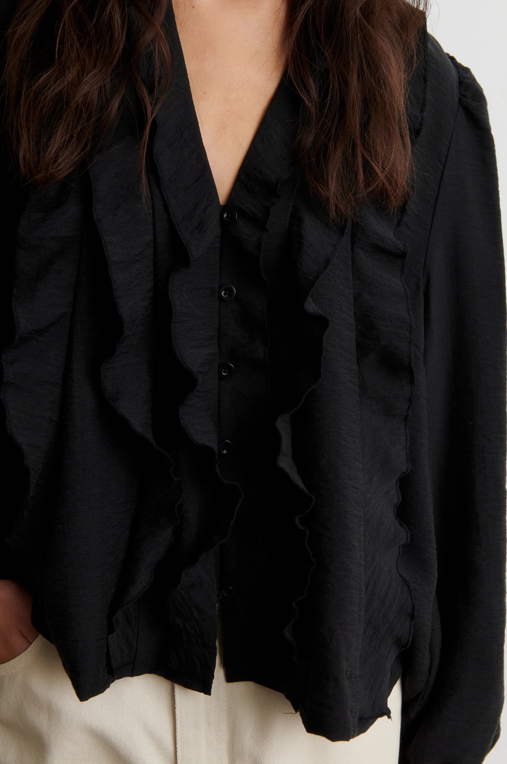 Close-up of Second Female Rayna black blouse layered V ruffle front