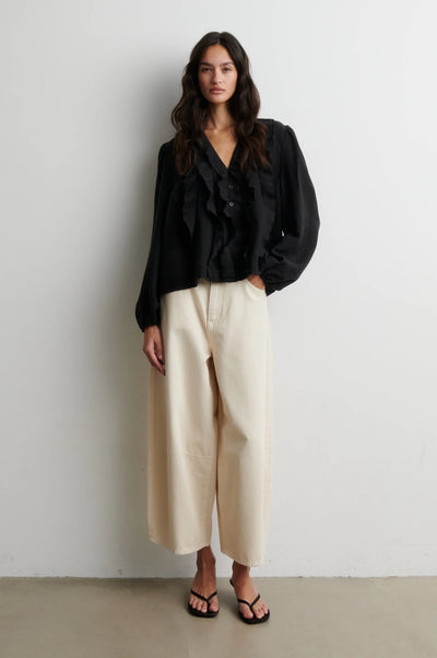 Second Female Rayna black ruffle v neck blouse styled with cream wide-leg trousers Second Female Rayna black ruffle blouse styled with cream wide-leg trousers